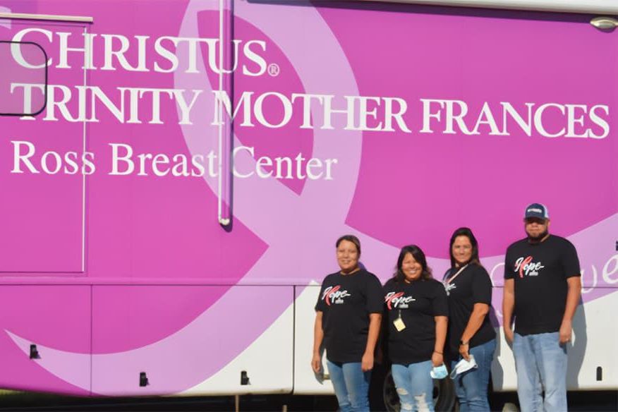 employees in front of a breast cancer bus